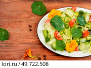 Rural salad with vegetables, nasturtium and dressing on wooden table.. Fresh herb salad with nasturtium flowers. Стоковое фото, агентство Ingram Publishing / Фотобанк Лори