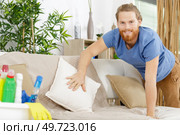 man is tidying up a sofa. Стоковое фото, агентство Ingram Publishing / Фотобанк Лори