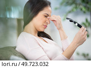 woman sitting on a sofa at home with a headache. Стоковое фото, агентство Ingram Publishing / Фотобанк Лори
