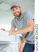 young happy man carrying washer. Стоковое фото, агентство Ingram Publishing / Фотобанк Лори