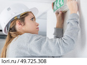 Woman mounting directional exit sign to wall. Стоковое фото, агентство Ingram Publishing / Фотобанк Лори