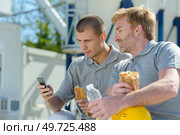 workmen on lunch break younger man using smartphone. Стоковое фото, агентство Ingram Publishing / Фотобанк Лори