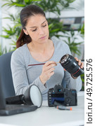 female cleaning dirty lens with a brush. Стоковое фото, агентство Ingram Publishing / Фотобанк Лори