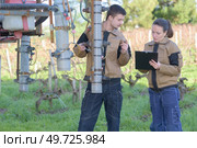 couple of agricultors inspecting machinery before harvesting. Стоковое фото, агентство Ingram Publishing / Фотобанк Лори