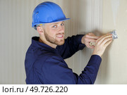 portrait of a tradesman scraping wallpaper off the wall. Стоковое фото, агентство Ingram Publishing / Фотобанк Лори
