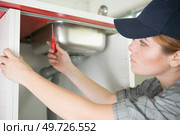 young woman fixes the plumbing under the kitchen sink. Стоковое фото, агентство Ingram Publishing / Фотобанк Лори