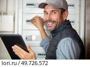 electrician smiling near switch box with tablet computor. Стоковое фото, агентство Ingram Publishing / Фотобанк Лори