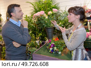 smiling woman seller offering flowers man. Стоковое фото, агентство Ingram Publishing / Фотобанк Лори