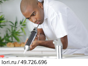 plumber putting a silicone sealant to installing a kitchen sink. Стоковое фото, агентство Ingram Publishing / Фотобанк Лори