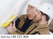 two working builders plastering a wall. Стоковое фото, агентство Ingram Publishing / Фотобанк Лори