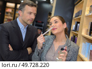 Lady smelling perfume, man looking on with serious expression. Стоковое фото, агентство Ingram Publishing / Фотобанк Лори