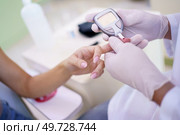 From above of crop anonymous hands of doctor in gloves checking blood sugar level of patient with glucometer in clinic. Doctor checking blood sugar level of patient in hospital. Стоковое фото, агентство Ingram Publishing / Фотобанк Лори