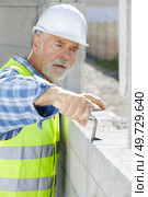 happy senior worker in hardhat with trowel installing brick masonry. Стоковое фото, агентство Ingram Publishing / Фотобанк Лори