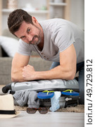 man trying to fit all clothing to packing his suitcase. Стоковое фото, агентство Ingram Publishing / Фотобанк Лори