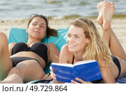 young woman laying on sunbed at beach with book. Стоковое фото, агентство Ingram Publishing / Фотобанк Лори