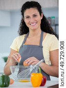 woman in kitchen cracking egg intoa bowl. Стоковое фото, агентство Ingram Publishing / Фотобанк Лори
