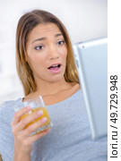 Young woman drinking and using her digital tablet. Стоковое фото, агентство Ingram Publishing / Фотобанк Лори