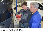 student with instructor repairing a car during apprenticeship. Стоковое фото, агентство Ingram Publishing / Фотобанк Лори