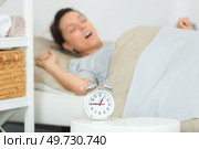 sleepy young woman stretching to turn alarm off. Стоковое фото, агентство Ingram Publishing / Фотобанк Лори