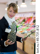 inspector checking pineapple in green grocers. Стоковое фото, агентство Ingram Publishing / Фотобанк Лори