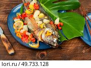 Fried tilapia fish with citrus sauce on leaf background.. Roasted whole tilapia with citrus sauce. Стоковое фото, агентство Ingram Publishing / Фотобанк Лори