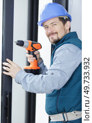 smiling worker fixing a window handle using a cordless screwdriver. Стоковое фото, агентство Ingram Publishing / Фотобанк Лори