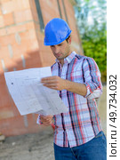 Architect reading blueprints on site. Стоковое фото, агентство Ingram Publishing / Фотобанк Лори