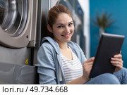 portrait of young woman holding digital tablet in laundromat. Стоковое фото, агентство Ingram Publishing / Фотобанк Лори