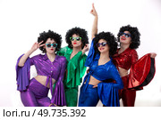 A group of girls in colorful flared suits and afro wigs pose against a white background. Disco style from the eighties or seventies. Стоковое фото, фотограф Лазаренко Светлана / Фотобанк Лори