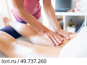 Crop female therapist rubbing oily leg of female client lying on stomach over spa table during physiotherapist massage session in clinic. Crop masseuse rubbing oily skin of client during body massage in clinic. Стоковое фото, агентство Ingram Publishing / Фотобанк Лори