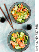Fresh Asian salad with smoked salmon, fresh cucumber and chopstick. Top view.. Fresh fish salad with raw cucumber. Стоковое фото, агентство Ingram Publishing / Фотобанк Лори