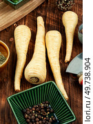Raw and uncooked parsnips roots on the kitchen table. Raw parsnip roots on wooden table. Стоковое фото, агентство Ingram Publishing / Фотобанк Лори
