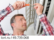 Man repairing an air conditioning unit. Стоковое фото, агентство Ingram Publishing / Фотобанк Лори