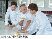 Senior chef showing cake to trainees. Стоковое фото, агентство Ingram Publishing / Фотобанк Лори