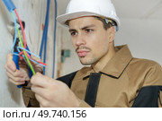 electrician attaching wires to socket in new building. Стоковое фото, агентство Ingram Publishing / Фотобанк Лори