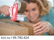 young woman taping up a cardboard box. Стоковое фото, агентство Ingram Publishing / Фотобанк Лори