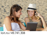 two young woman on beach with tablet and smartphone. Стоковое фото, агентство Ingram Publishing / Фотобанк Лори