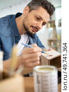 man is painting a wood box. Стоковое фото, агентство Ingram Publishing / Фотобанк Лори