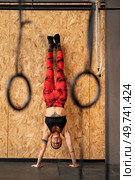 Vertical photo of a sportive mature woman performing handstand exercise in the gym. Woman performing handstand exercise in the gym. Стоковое фото, агентство Ingram Publishing / Фотобанк Лори