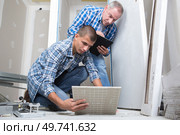 a young builder laying tiles. Стоковое фото, агентство Ingram Publishing / Фотобанк Лори