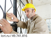 builder sanding a metal fence. Стоковое фото, агентство Ingram Publishing / Фотобанк Лори