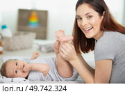 mother putting diaper on her happy baby in nursery. Стоковое фото, агентство Ingram Publishing / Фотобанк Лори