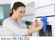 woman cleaning oven with spray. Стоковое фото, агентство Ingram Publishing / Фотобанк Лори