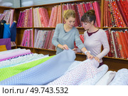 beautiful female workers choosing fabric skeins in textile shop. Стоковое фото, агентство Ingram Publishing / Фотобанк Лори