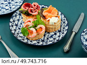 Puff pastry tartlets with fish, shrimp and bacon on a plate on the table.. Tartlets with seafood and bacon, tasty snack. Стоковое фото, агентство Ingram Publishing / Фотобанк Лори