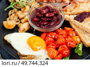 Full English breakfast of scrambled eggs, roasted bacon, toast and beans. Close up.. Full English breakfast on a plate. Стоковое фото, агентство Ingram Publishing / Фотобанк Лори