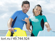 happy couple with boogie-boards making hang loose gesture. Стоковое фото, агентство Ingram Publishing / Фотобанк Лори