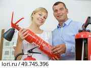 couple comparing fire extinguishers at hardware store. Стоковое фото, агентство Ingram Publishing / Фотобанк Лори