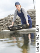 female worker tidying up oysters baskets. Стоковое фото, агентство Ingram Publishing / Фотобанк Лори