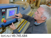 worker at workshop operating punch press machine tool by computer. Стоковое фото, агентство Ingram Publishing / Фотобанк Лори